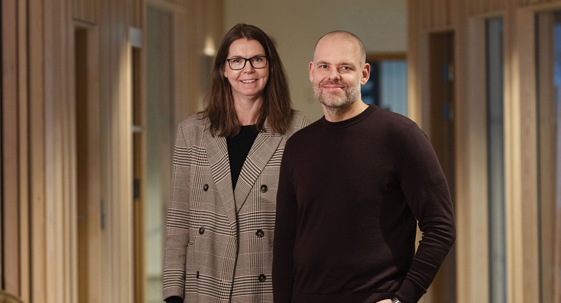 Medarbetarna Paul Roos och Petra Nilsson står bredvid varandra och tittar in i kameran med ett leende.