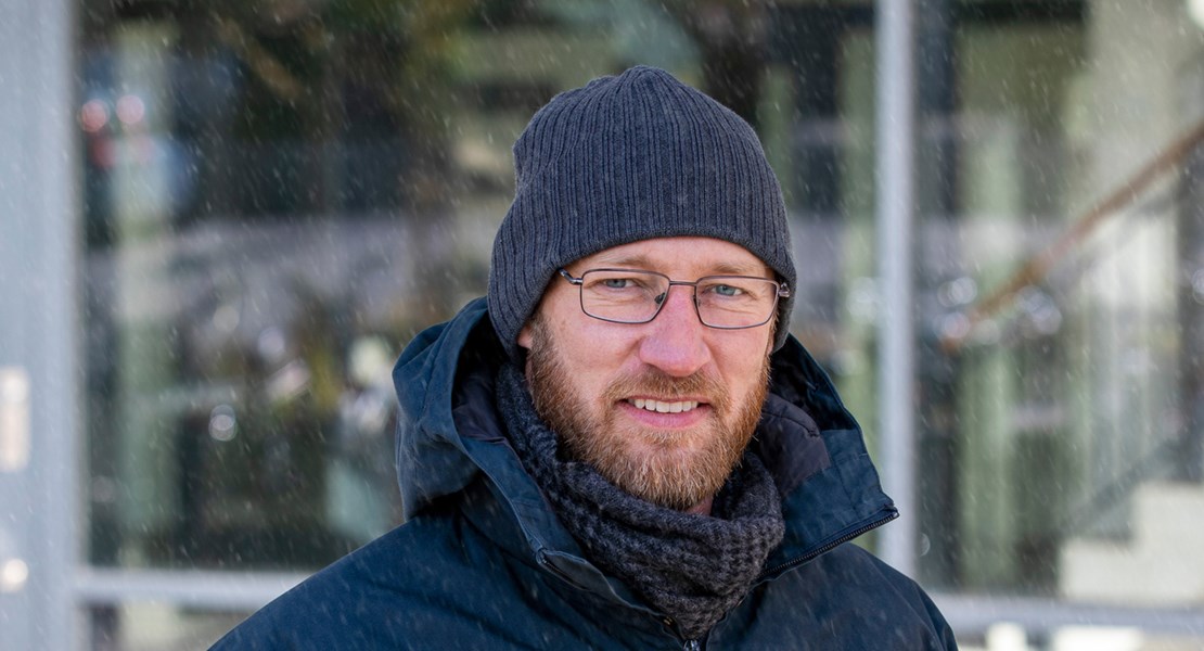 Daniel Sjödén står utomhus i snöfall iklädd jacka, mössa och glasögon.