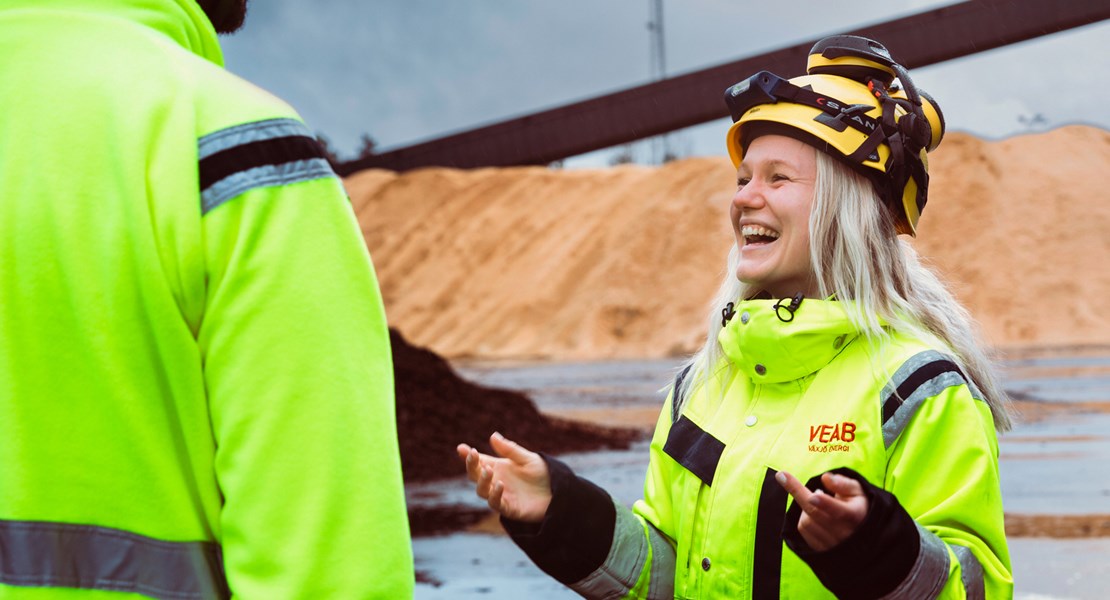 Medarbetare på Växjö Energi i gulkläder och hjälm ler mot en kollega