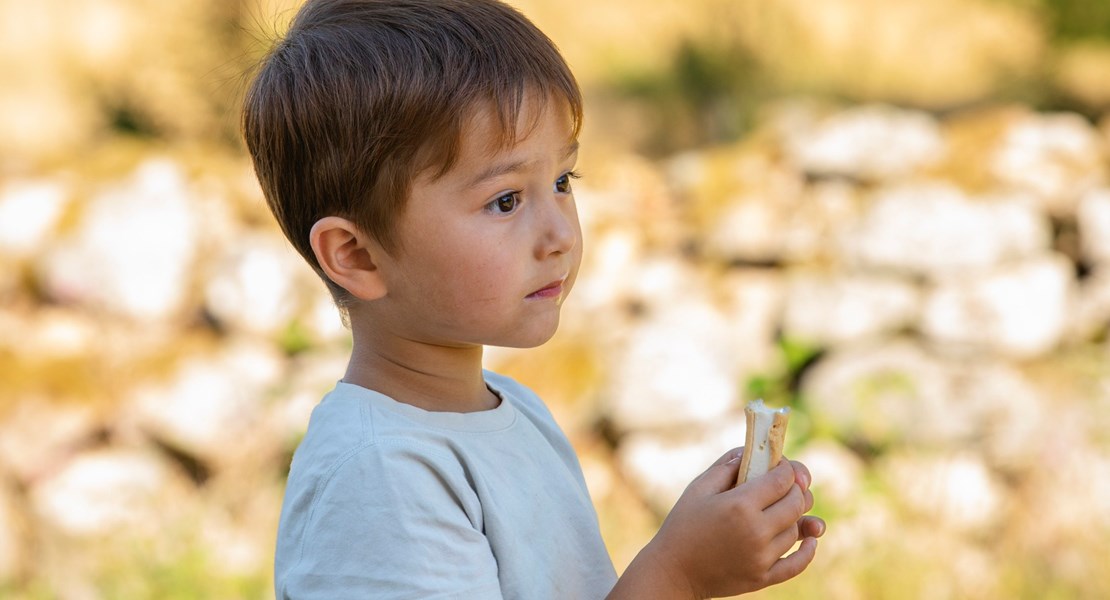 5-årig pojke håller i en glass, bakgrunden är i oskärpa.